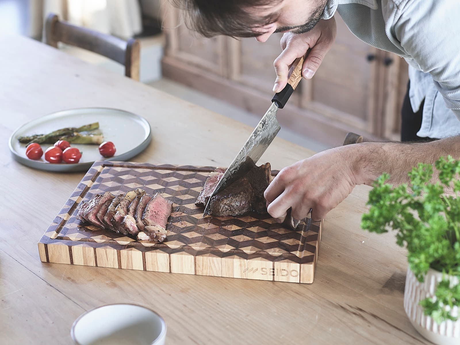 Slicing steak with the SEIDO chef's knife on an end-grain chopping board