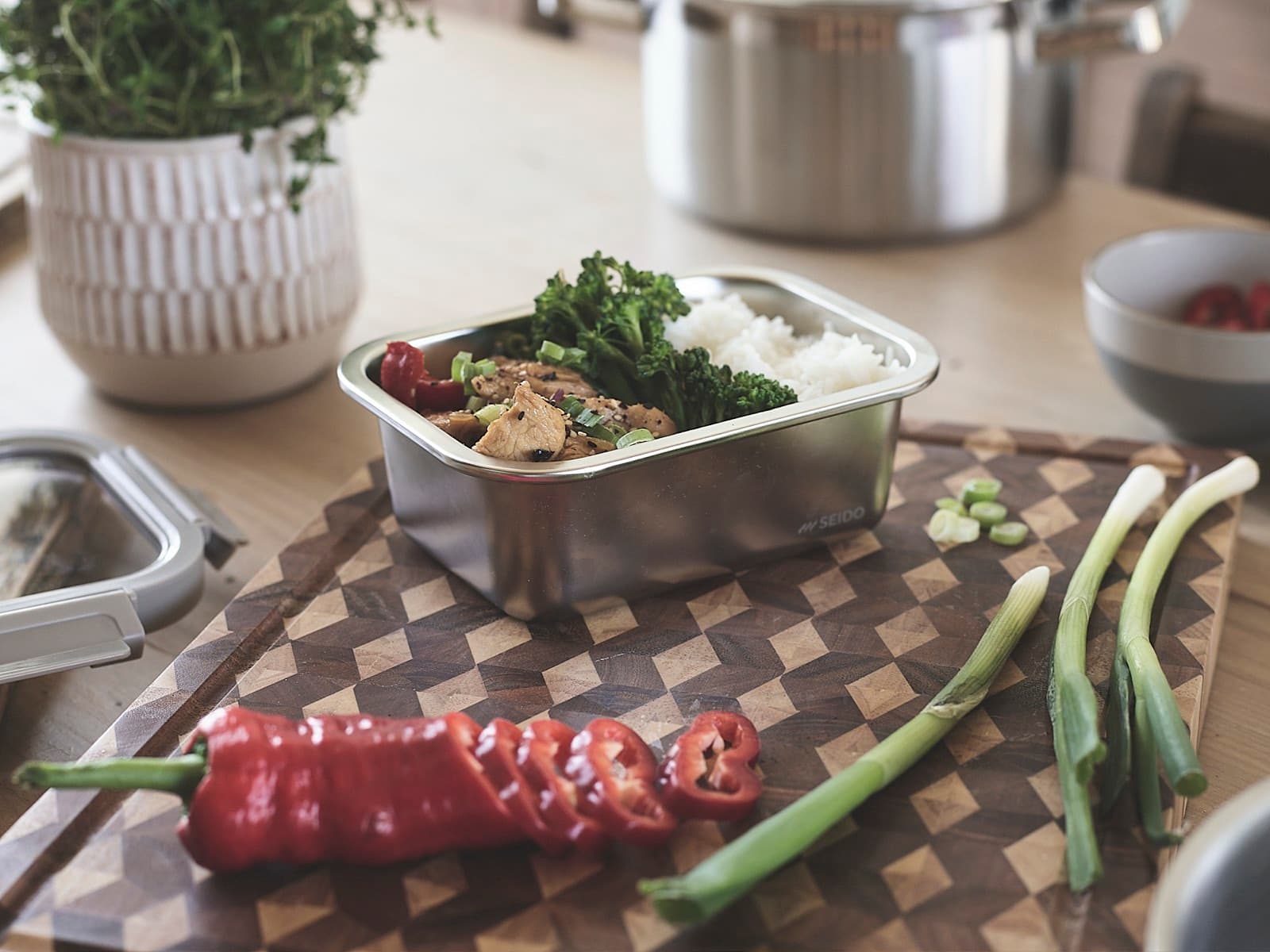 SEIDO stainless steel lunch box filled with chicken, broccoli and rice on a wooden chopping board