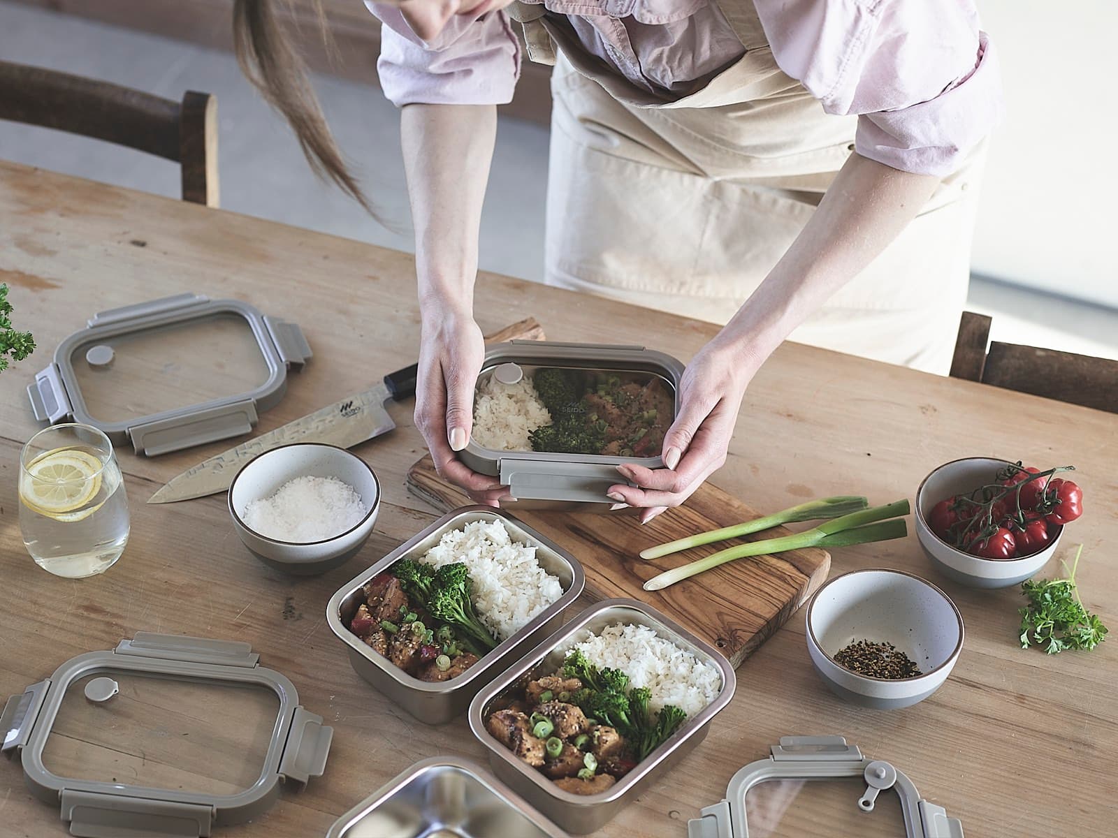 Hands setting down a packed stainless steel lunch box