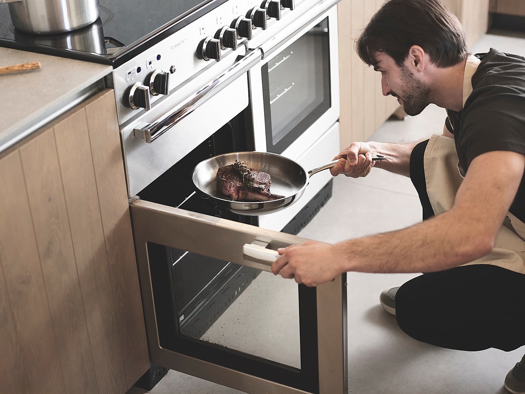 Putting an uncoated stainless steel frying pan with a steak into the oven, without its lid