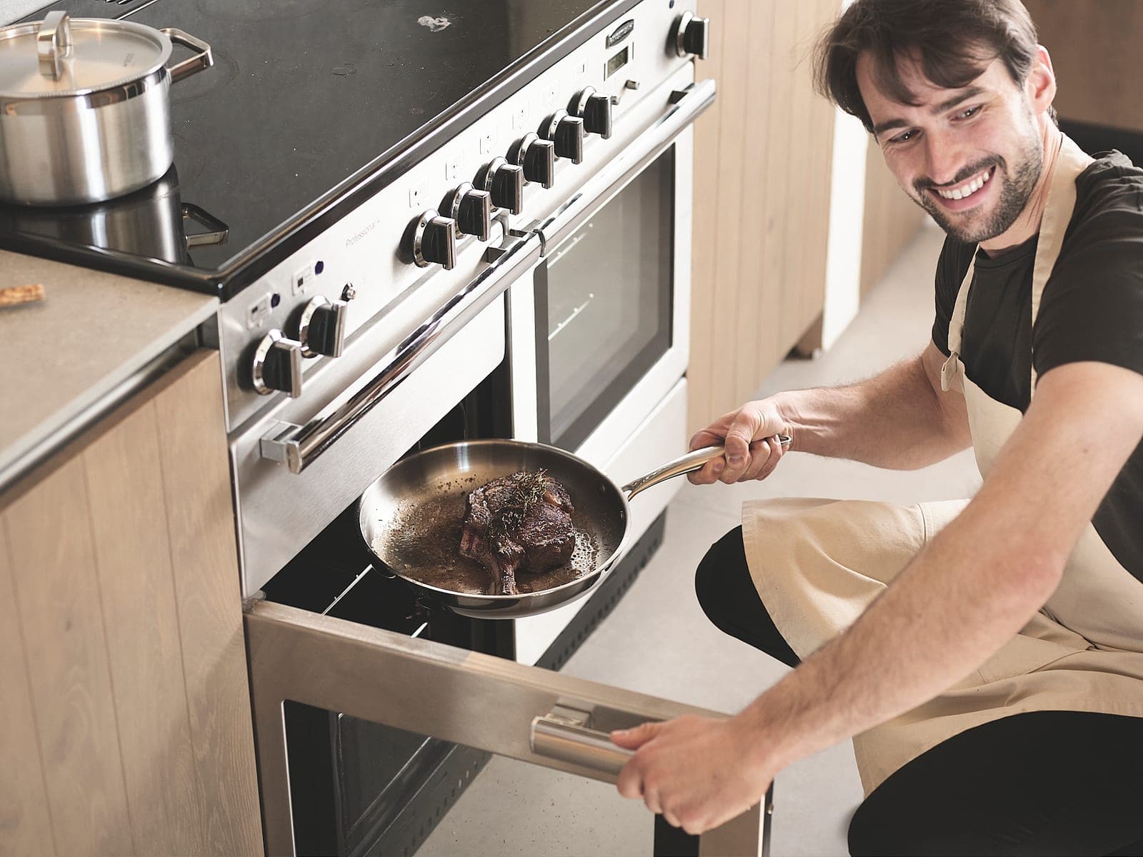 Taking a stainless steel frying pan out of the oven